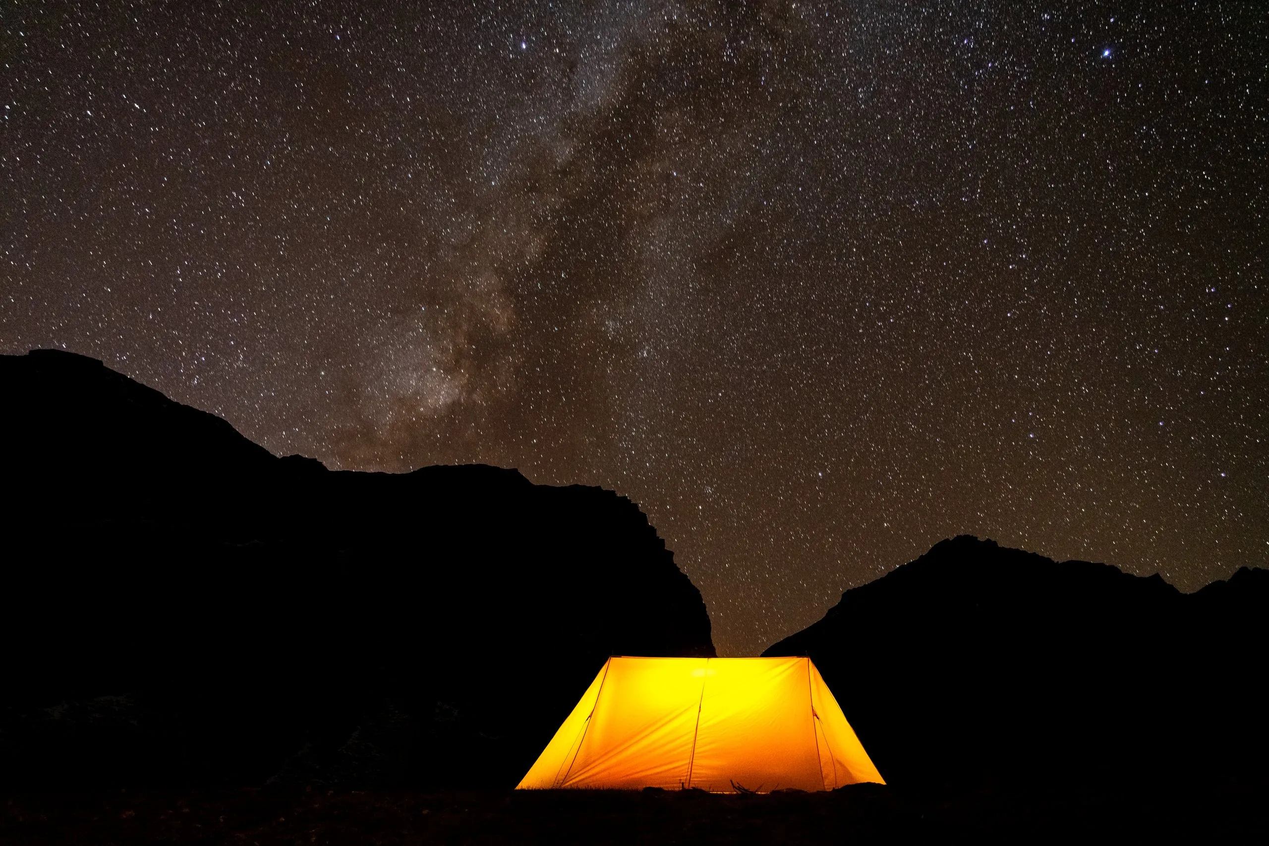 Glowing yellow tent beneath the Milky Way in a high mountain camp, Snowman Trek, Bhutan